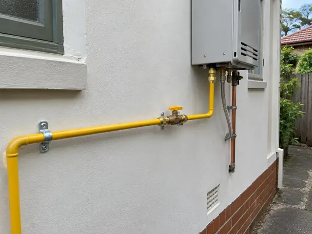 Exterior wall with yellow gas piping and wall-mounted gas unit beside a window in Beecroft